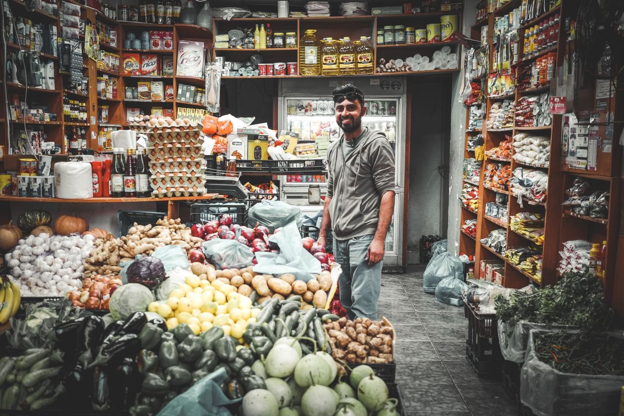 Free Smiling man in Athenian grocery store surrounded by colorful fruits and vegetables. Stock Photo